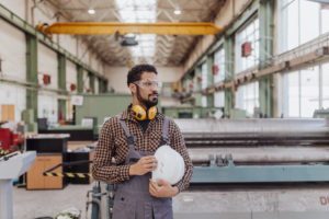 Heavy Industry Worker With Safety Headphones And Hard Hat In Industrial Factory - GTS